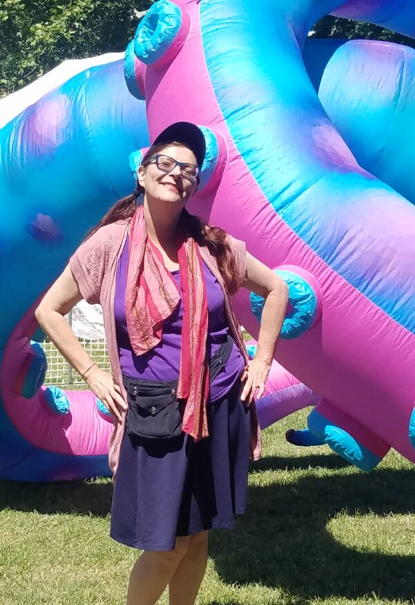 BJ Sikes author in front of a pink purple and blue bounce house.